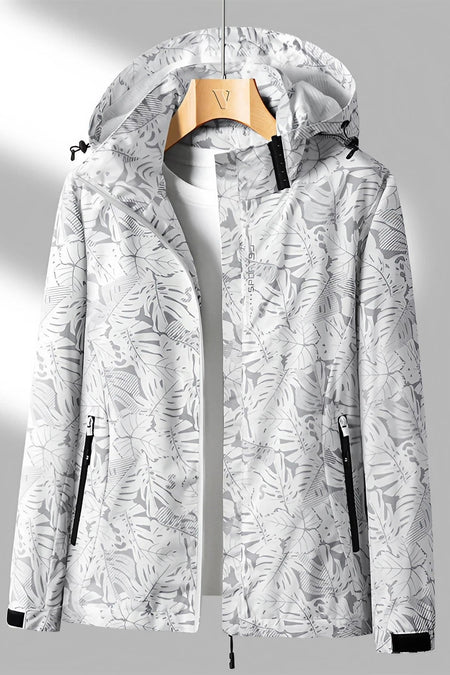 Veste imperméable à capuche blanche avec motif floral, fermeture éclair noire, poches zippées, suspendue sur un cintre en bois. Mode outdoor tendance.