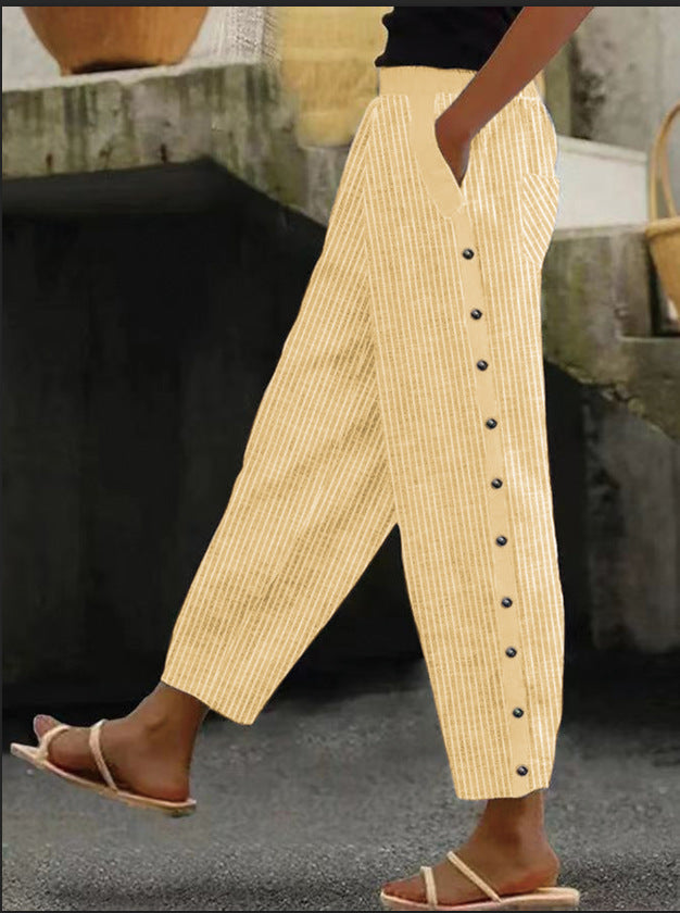 Pantalon jaune à rayures verticales avec boutons latéraux, porté par une personne marchant en sandales. Mode estivale, style décontracté.