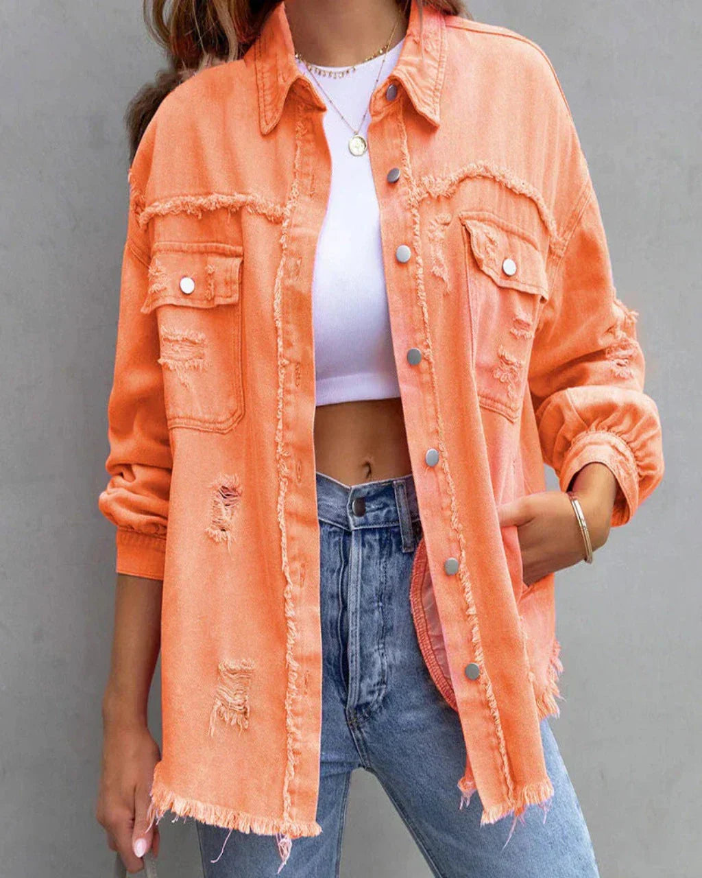Femme portant une veste en jean orange délavée, style décontracté, avec un t-shirt blanc et un jean bleu. Mode tendance, look urbain chic.