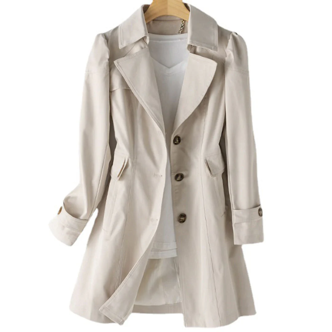 Manteau trench beige élégant pour femme, avec col large et boutons marron, suspendu sur un cintre en bois. Mode automne chic et intemporelle.