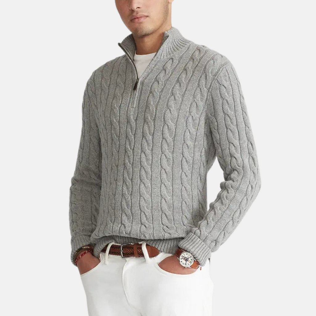 Homme portant un pull torsadé gris avec fermeture éclair, manches longues, sur fond blanc. Mode masculine élégante, tenue décontractée chic.