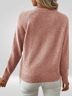 Femme portant un pull rose en tricot à manches longues, vue de dos, sur fond gris. Mode automne-hiver, style décontracté et élégant.