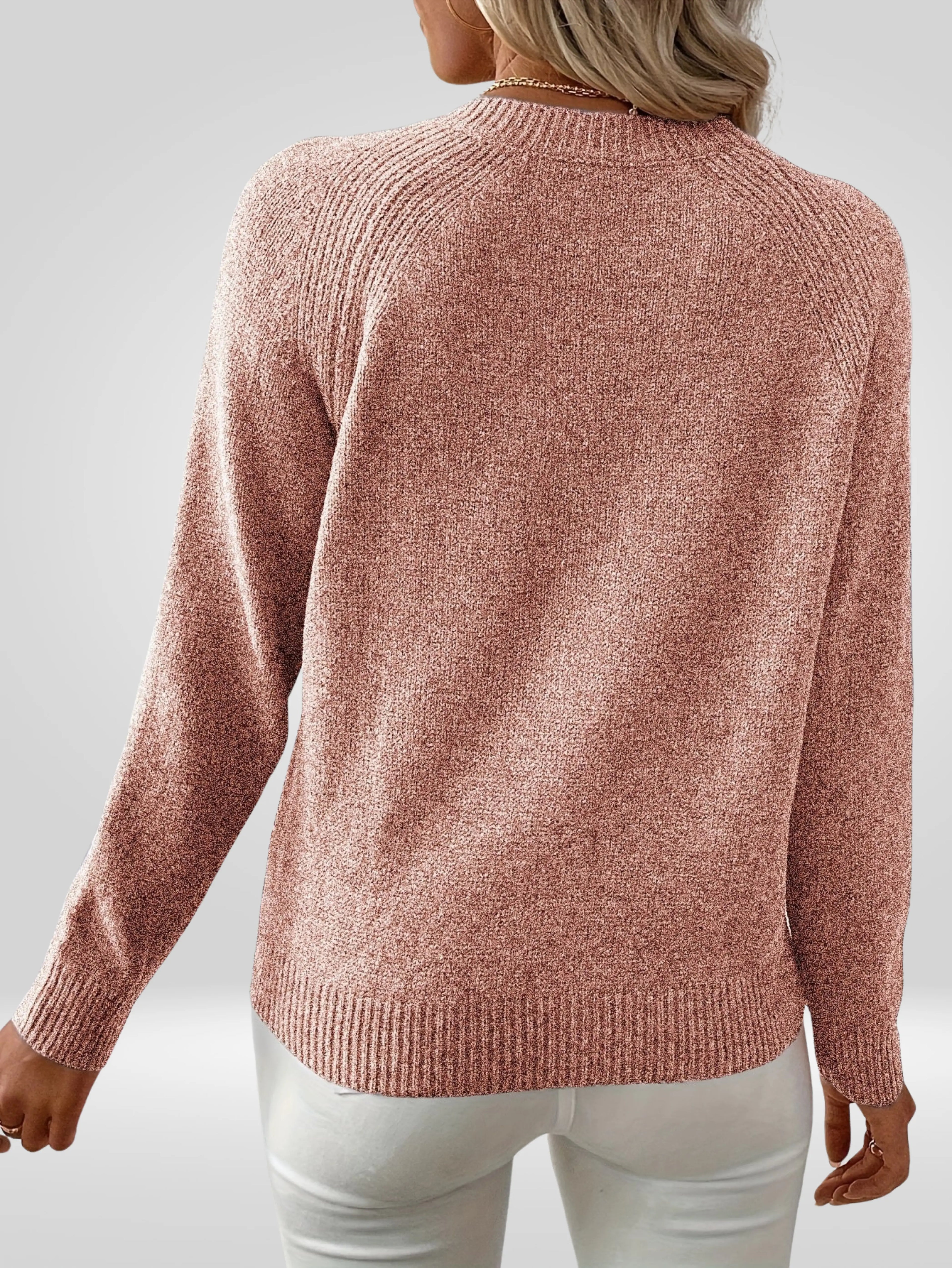 Femme portant un pull rose en tricot à manches longues, vue de dos, sur fond gris. Mode automne-hiver, style décontracté et élégant.