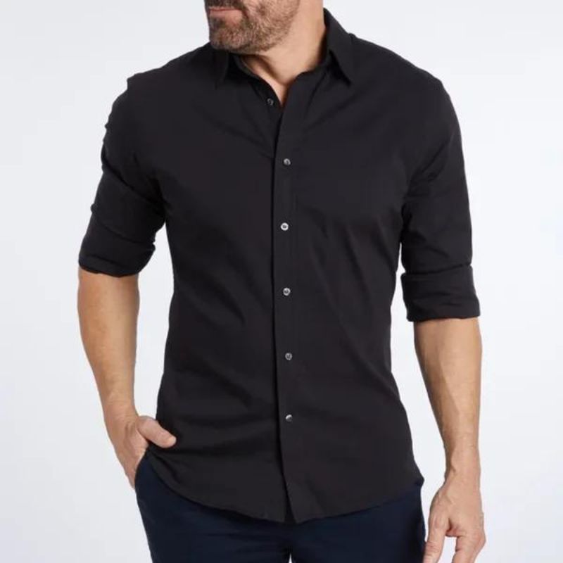 Homme portant une chemise noire élégante à manches longues, boutons argentés, style décontracté-chic, mode masculine moderne, fond blanc.