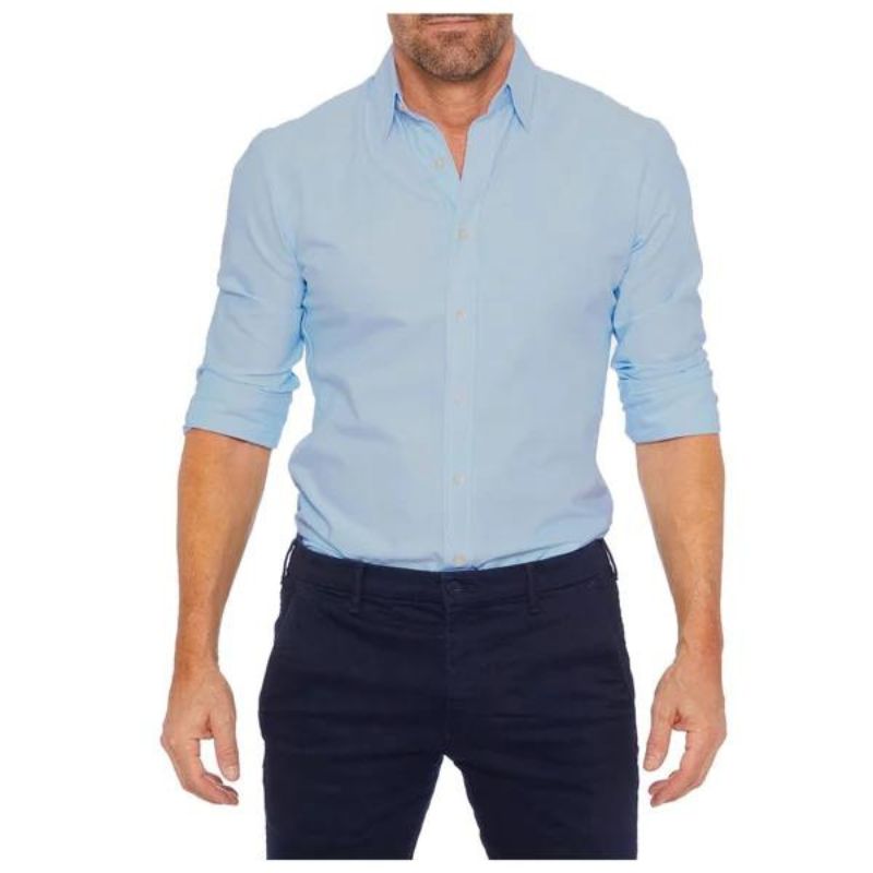 Chemise homme bleu clair, manches retroussées, col classique, portée avec un pantalon noir. Mode masculine élégante et décontractée.