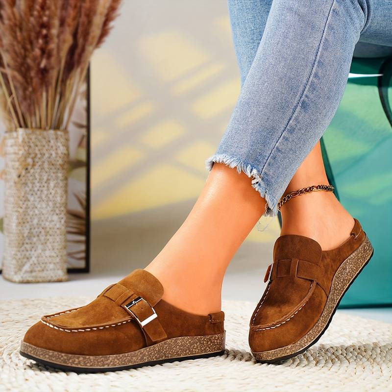 Chaussures mocassins marron en daim pour femme, avec boucle métallique, portées avec un jean décontracté. Mode féminine, tendance automne.