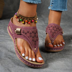 Sandales violettes en cuir avec motifs ajourés, portées avec un bracelet de cheville coloré et un jean. Mode estivale, chaussures tendance.