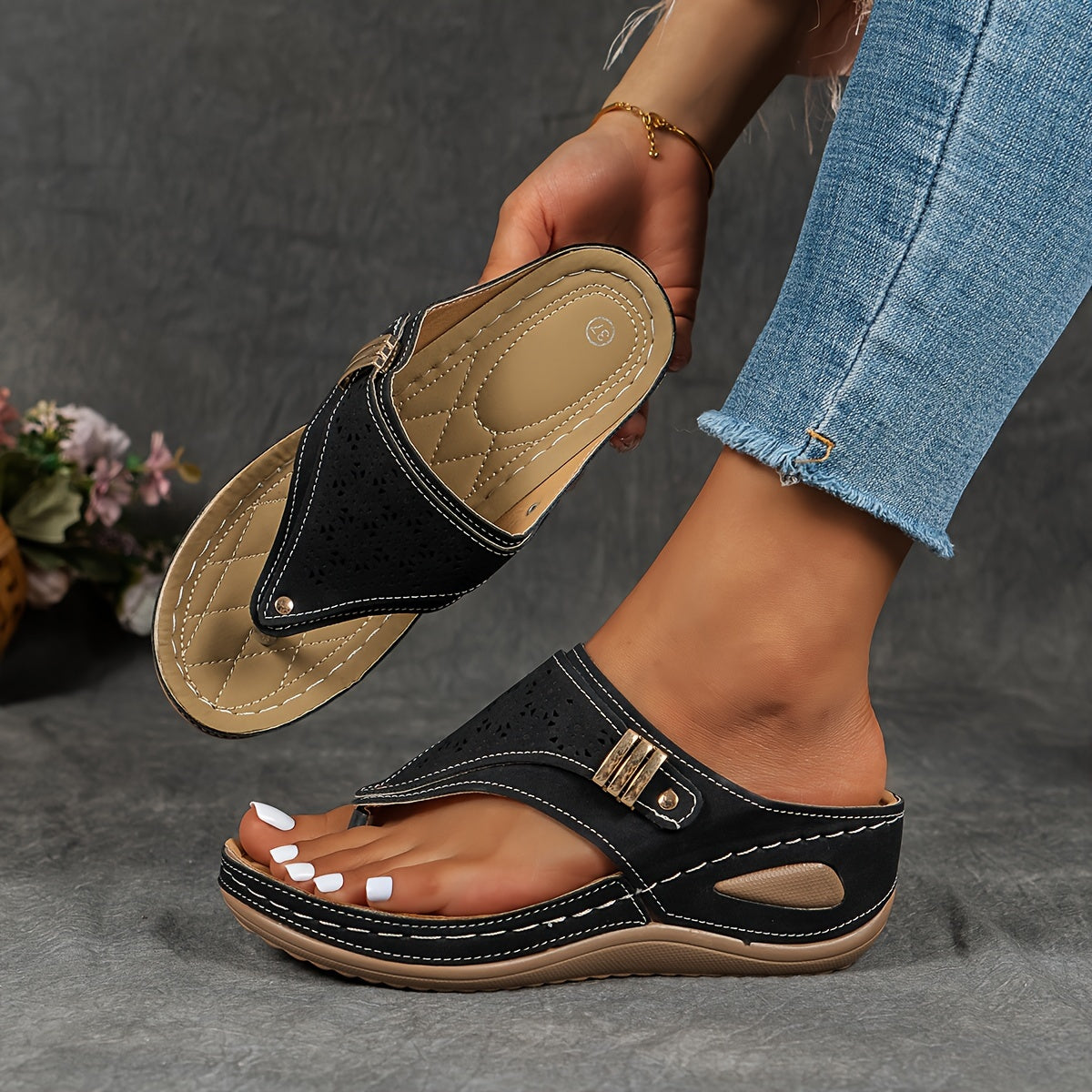 Sandales noires en cuir pour femme, design moderne avec semelle compensée, portées avec un jean. Chaussures d'été élégantes et confortables.