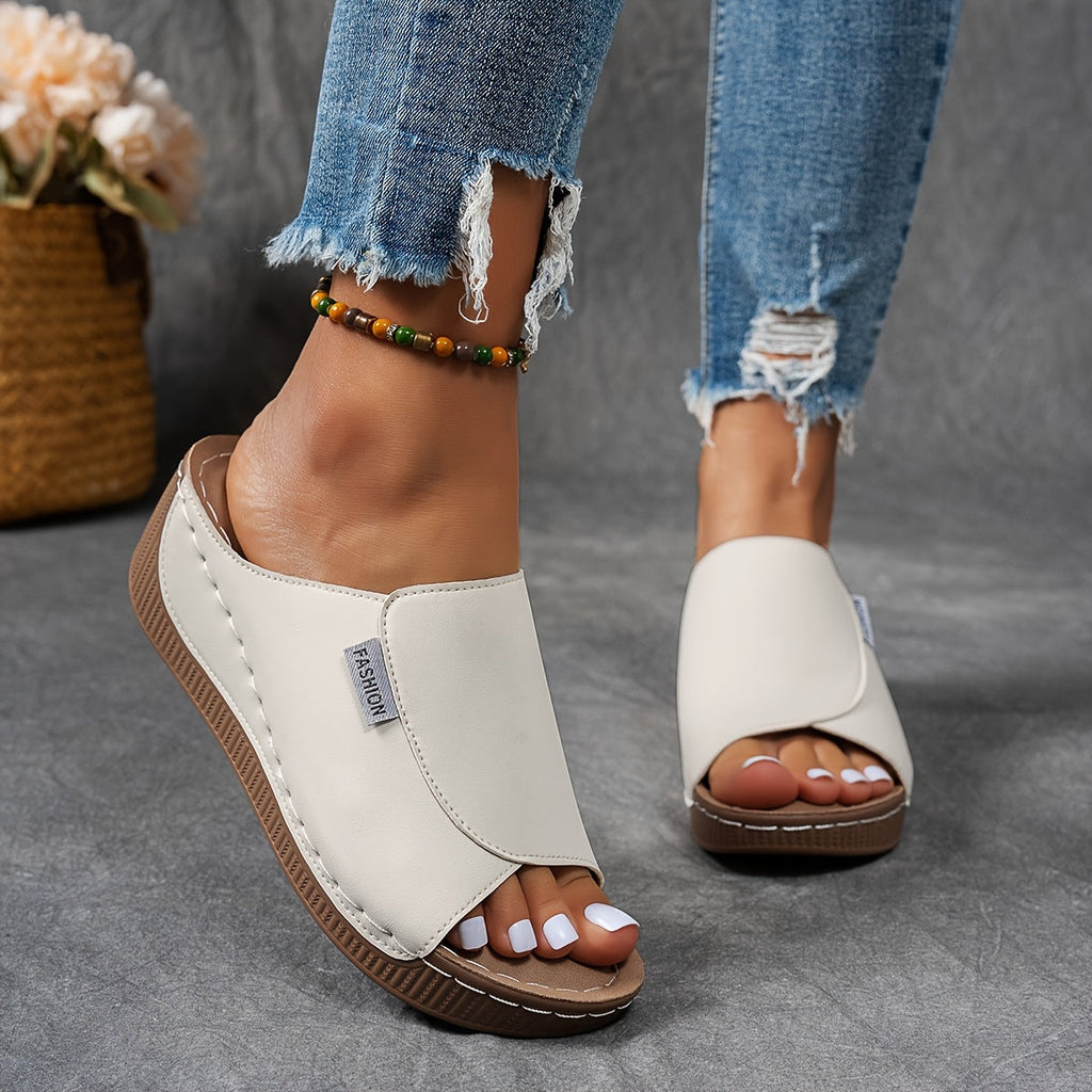Sandales blanches ouvertes pour femme, avec semelle compensée marron, portées avec un jean déchiré. Mode estivale, chaussures confortables.