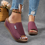 Sandales pour femmes en cuir bordeaux, talon compensé, portées avec un jean déchiré. Mode estivale, confort, style décontracté.