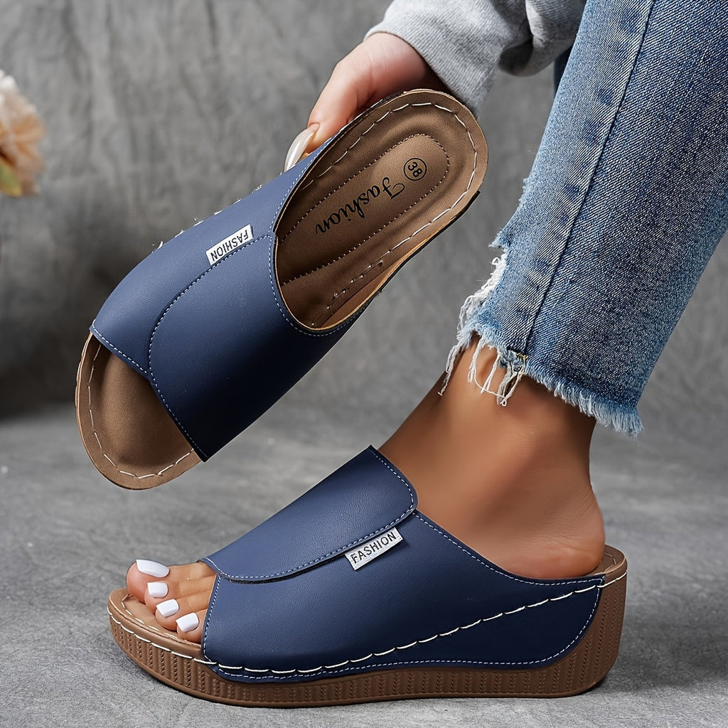 Sandales compensées bleues pour femme, design moderne, semelle en cuir, portées avec un jean décontracté. Mode estivale, confort et style.