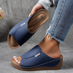 Sandales compensées bleues pour femme, design moderne, semelle en cuir, portées avec un jean décontracté. Mode estivale, confort et style.