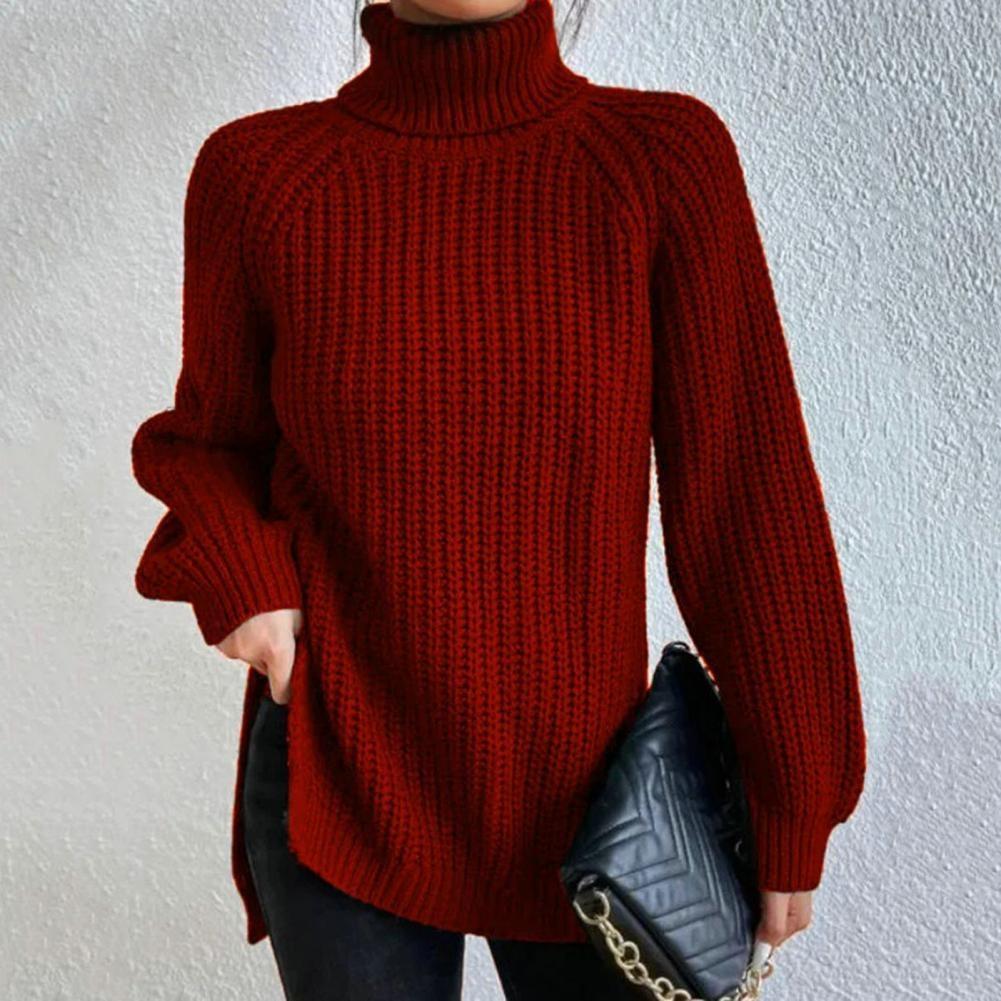 Femme portant un pull rouge à col roulé en maille épaisse, tenant un sac à main noir matelassé avec chaîne dorée. Mode automne-hiver élégante.