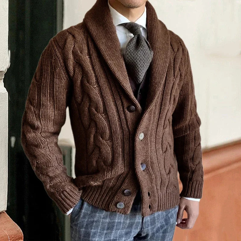 Homme portant un cardigan marron en maille torsadée, chemise blanche et cravate grise, style élégant et décontracté, mode masculine automne-hiver.