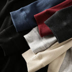 Manches de pulls en tricot côtelé multicolores, noir, bleu, rouge, gris, beige, empilés. Mode hiver, vêtements chauds, style décontracté.