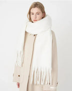 Femme portant une écharpe blanche épaisse en laine, manteau beige, style hiver, mode féminine élégante, accessoires chauds, tendance automne-hiver.