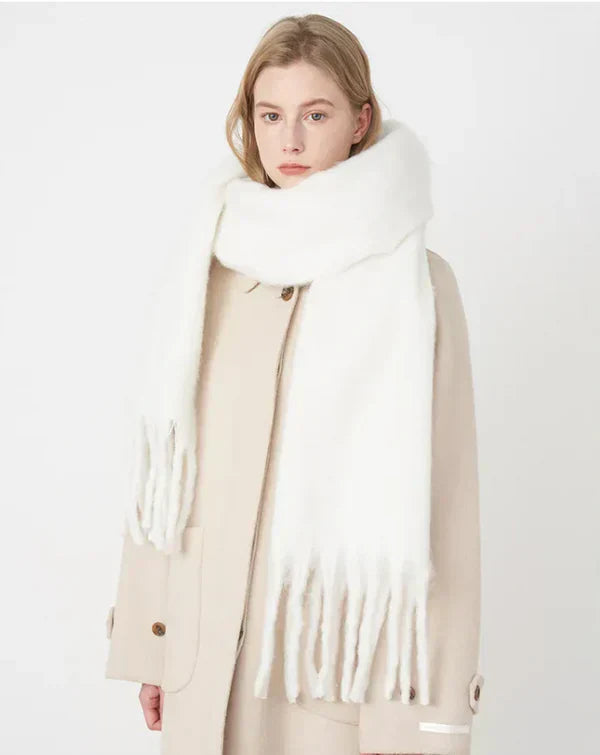 Femme portant une écharpe blanche épaisse en laine, manteau beige, style hiver, mode féminine élégante, accessoires chauds, tendance automne-hiver.
