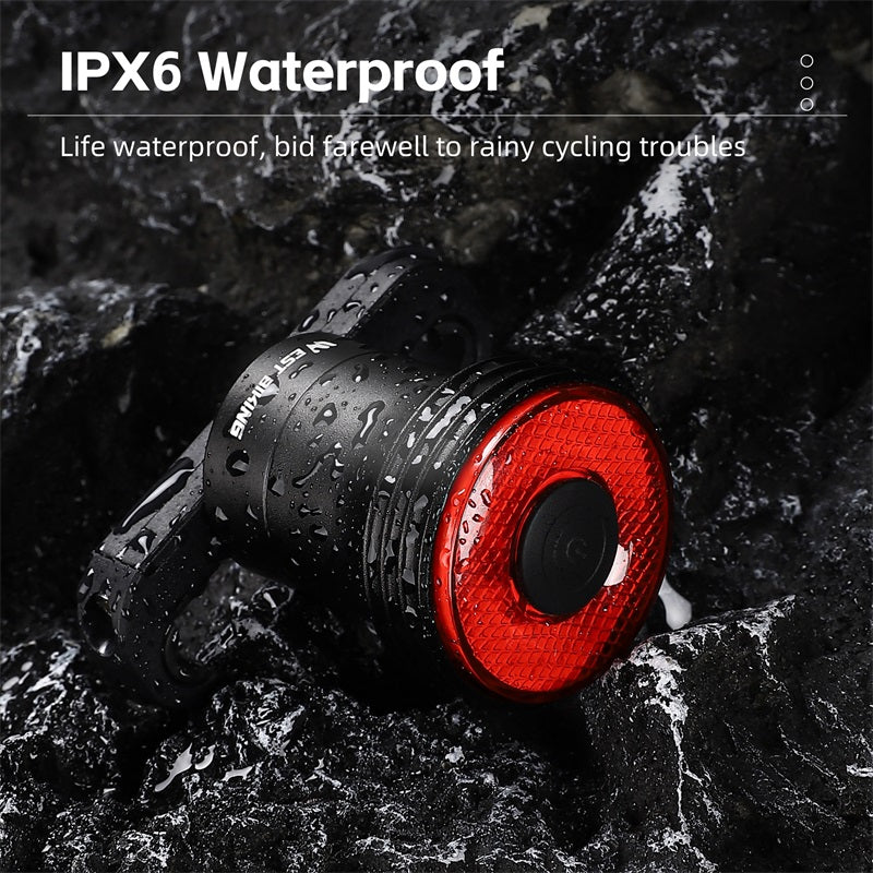 Lampe de vélo étanche IPX6, rouge et noire, sur fond rocheux mouillé. Accessoire de cyclisme résistant à l'eau pour sécurité et visibilité.