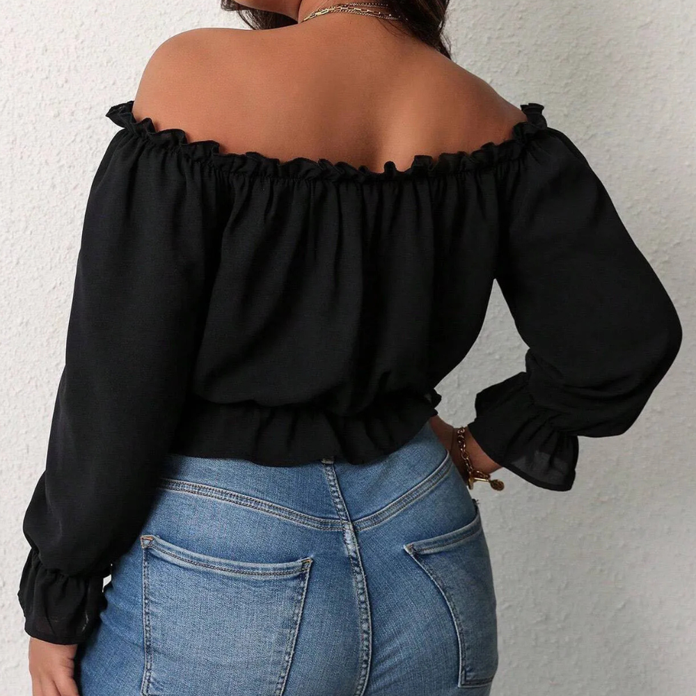Blouse noire à épaules dénudées, manches longues, portée avec un jean bleu. Mode féminine élégante, style décontracté chic.