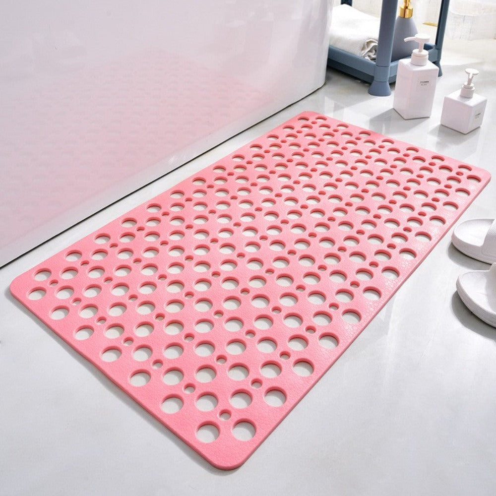 Tapis de bain antidérapant rose avec trous, posé sur un sol de salle de bain blanc. Accessoires de bain en arrière-plan. Idéal pour sécurité douche.