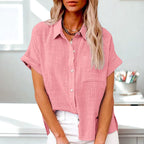 Femme portant une chemise rose en lin, manches courtes, col ouvert, posant dans un intérieur moderne. Mode féminine, tenue décontractée élégante.