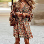 Robe bohème chic à motifs floraux, manches longues, ceinture nouée, portée par une femme en extérieur. Mode féminine tendance automne.