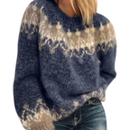 Pull en laine bleu avec motifs géométriques beige et blanc, manches longues, col rond, porté par une femme. Mode hiver, tendance cosy.