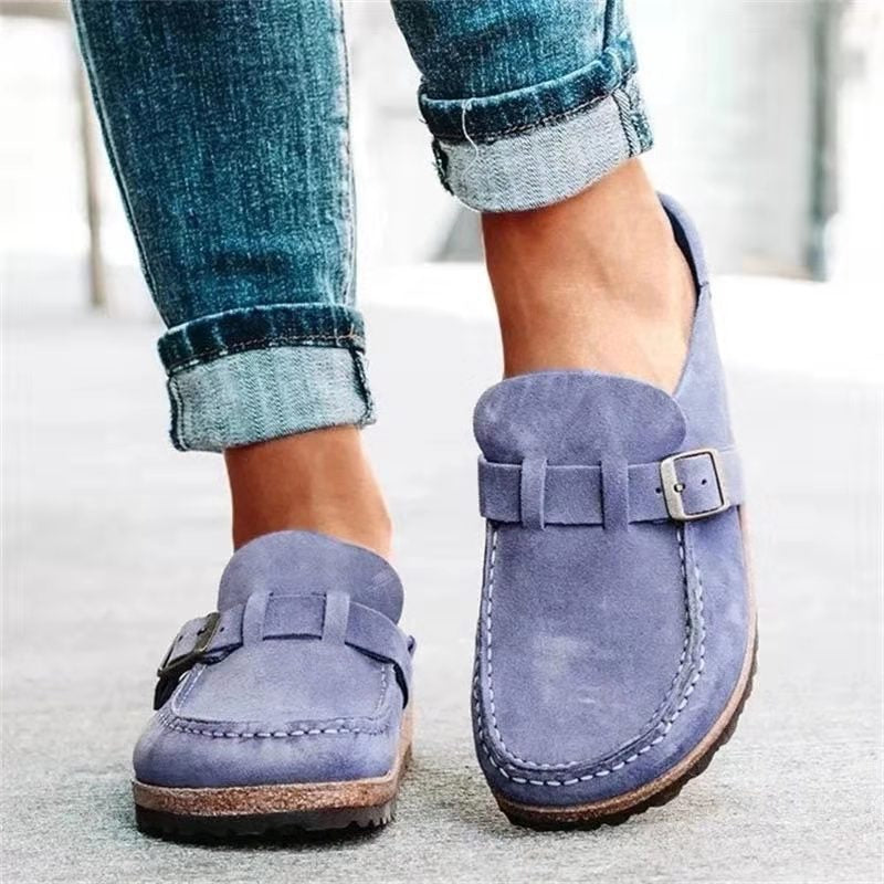 Chaussures mocassins en daim bleu pour femme, avec boucle décorative, portées avec un jean retroussé. Mode féminine, style décontracté.