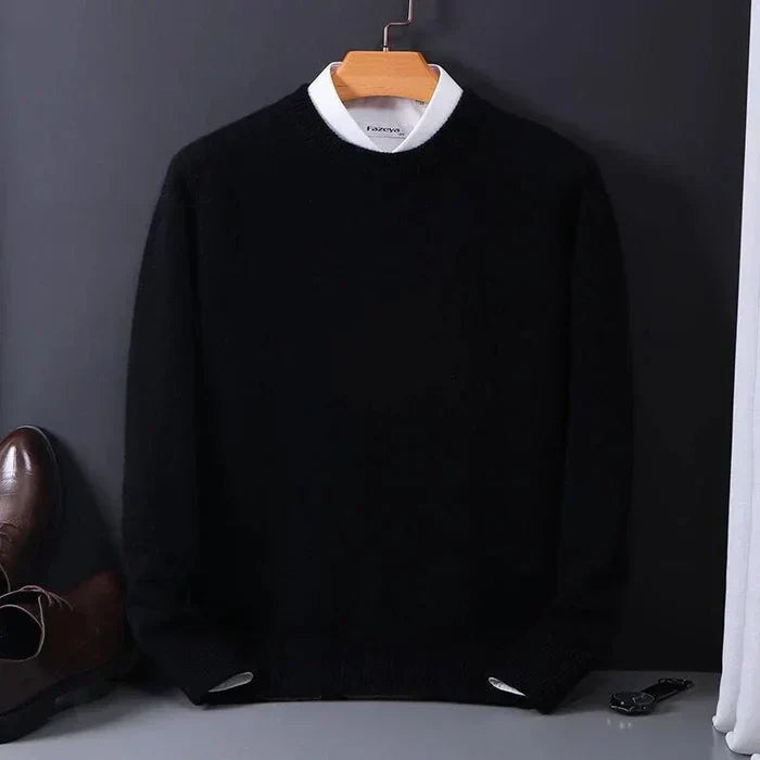 Pull noir élégant pour homme sur cintre, col rond, manches longues, posé à côté de chaussures en cuir marron. Mode masculine chic et intemporelle.