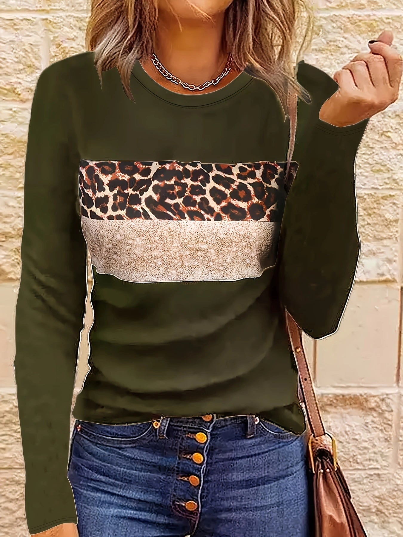 Femme portant un pull vert à motif léopard et bande beige, associé à un jean à boutons. Mode automne, style décontracté, tendance féminine.