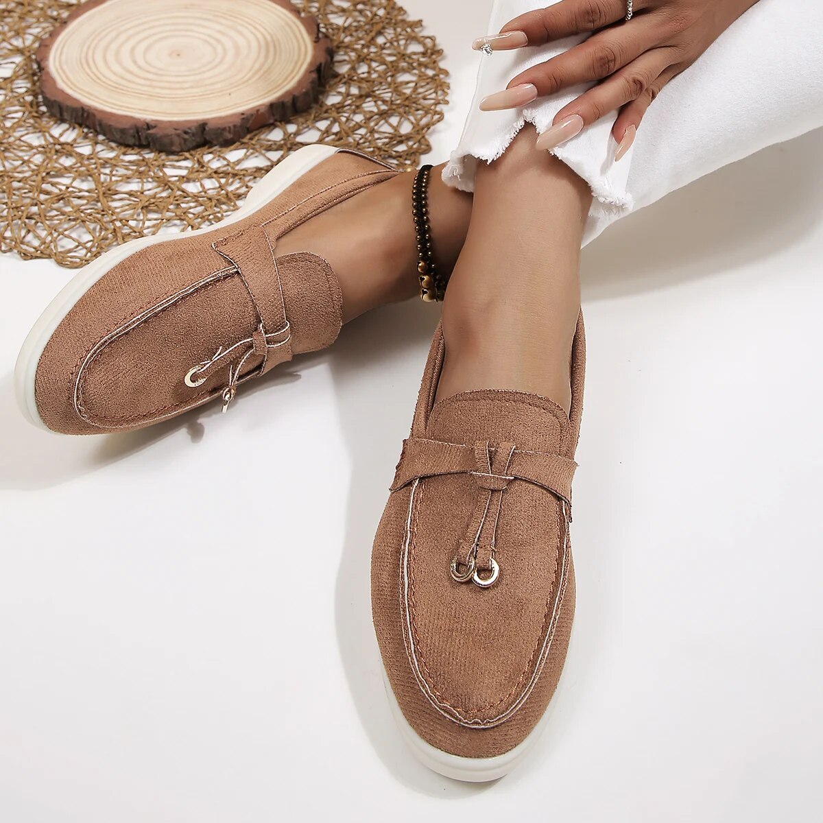 Chaussures mocassins marron pour femme, élégantes et confortables, portées avec un pantalon blanc. Mode féminine, style décontracté chic.