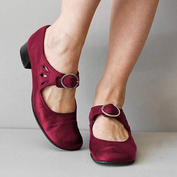 Chaussures rouges à talons bas avec boucle, portées par une personne debout. Style élégant et confortable, idéal pour la mode féminine.