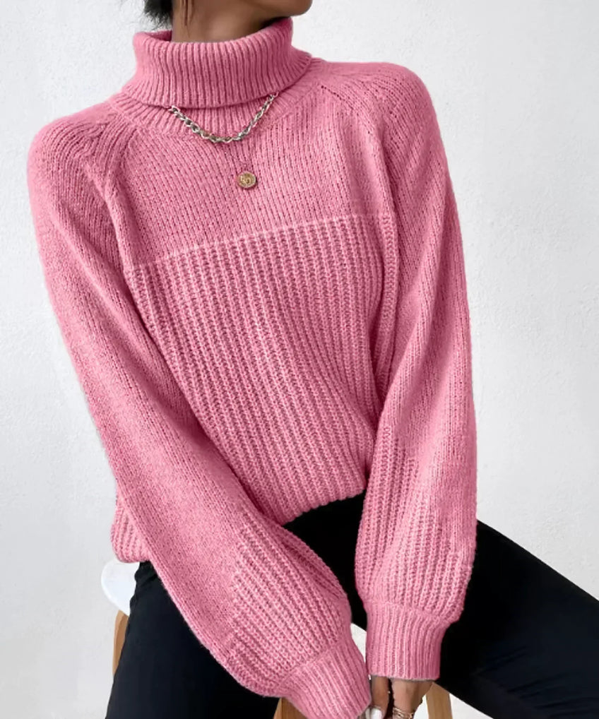 Pull rose à col roulé en maille épaisse, manches longues, porté avec un collier doré. Mode femme automne-hiver, style décontracté et élégant.