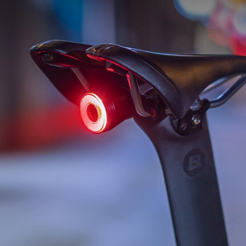 Selle de vélo avec feu arrière LED rouge allumé, sécurité cycliste, accessoire vélo nocturne, éclairage vélo urbain, visibilité accrue.