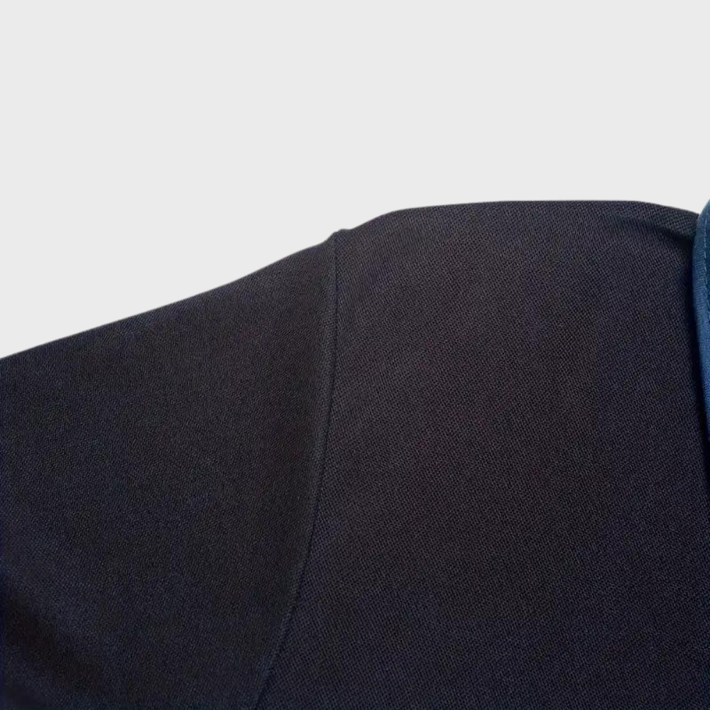 Épaule de veste noire en tissu texturé, couture visible, fond blanc. Mode masculine, vêtement élégant, détail couture veste.