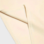 Tissu beige en microfibre, gros plan sur les coutures et la texture douce. Idéal pour vêtements confortables et respirants.