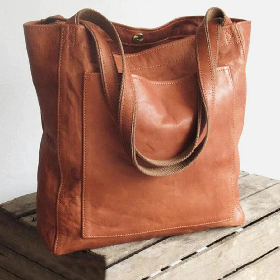Sac cabas en cuir marron sur une caisse en bois, design élégant et pratique, idéal pour le shopping ou le bureau. Accessoire mode tendance.