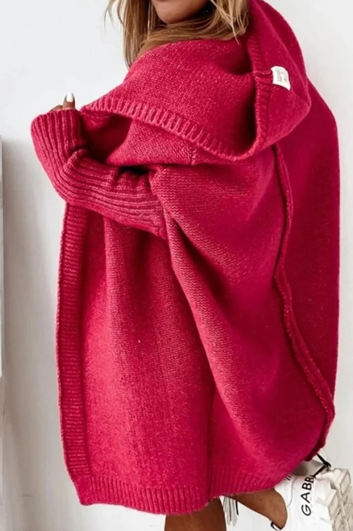 Femme portant un cardigan oversize en laine rouge vif, manches longues, capuche, style décontracté. Mode automne-hiver, tendance cosy.