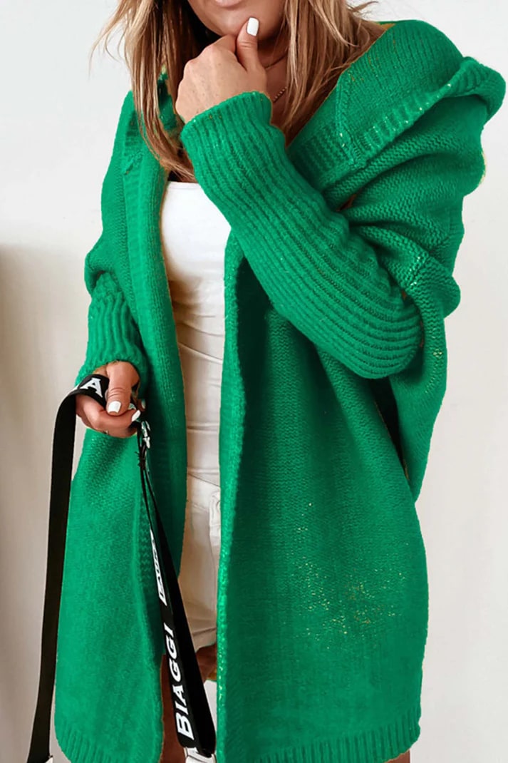 Femme portant un cardigan vert en tricot, manches longues, avec capuche. Mode automne, style décontracté, tendance féminine.