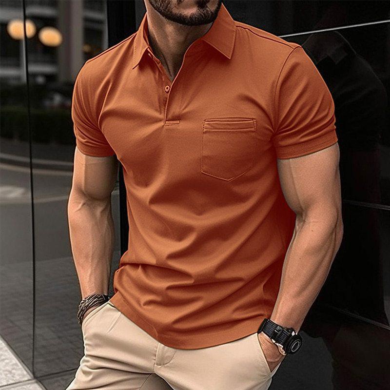 Homme portant un polo orange ajusté, manches courtes, avec poche poitrine, montre noire, bracelet, pantalon beige, en extérieur urbain.