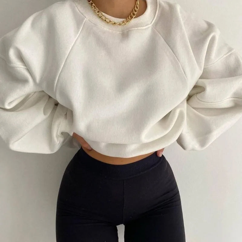 Femme portant un sweat-shirt blanc ample et un collier doré, associée à un legging noir. Mode décontractée, tendance et élégante.