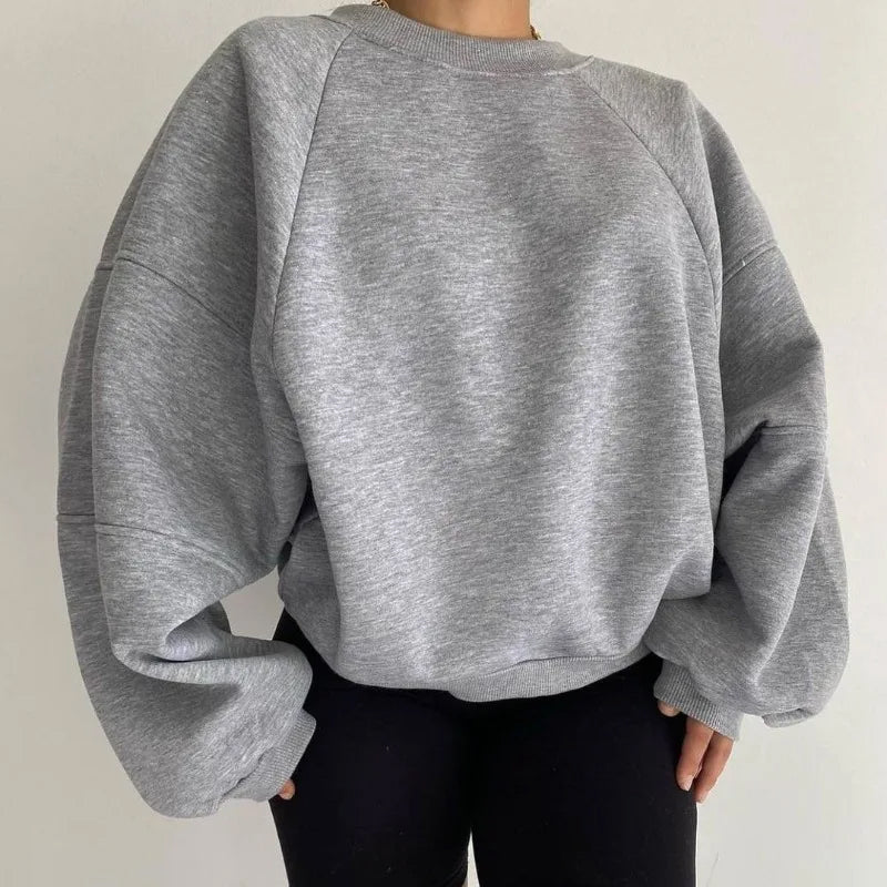 Pull gris oversize en coton, manches longues, porté par une personne. Style décontracté, tendance mode automne-hiver, idéal pour un look confortable.