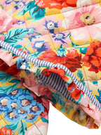 Couverture matelassée colorée avec motifs floraux vibrants et bordure rayée bleue, idéale pour décoration intérieure et confort.