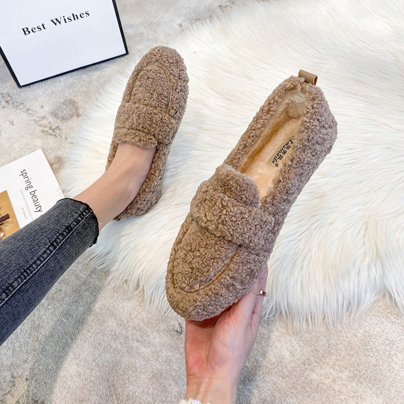 Mocassins en peluche marron pour femme sur tapis blanc, style décontracté et confortable, parfaits pour l'hiver. Chaussures tendance et chaudes.