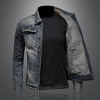 Veste en jean délavé pour homme, style moderne, manches longues, avec t-shirt noir en dessous, sur fond gris. Mode masculine tendance.