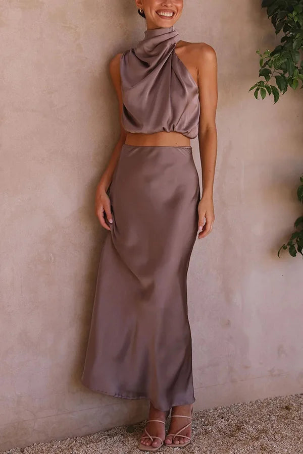 Robe longue en satin taupe, sans manches, col haut, élégante et moderne, portée par une femme, idéale pour soirées et événements chics.
