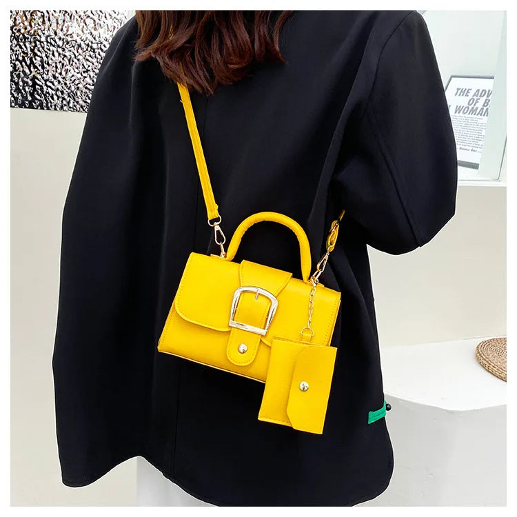 Sac à main jaune vif avec bandoulière et pochette assortie, porté par une personne en manteau noir. Accessoire de mode tendance et coloré.