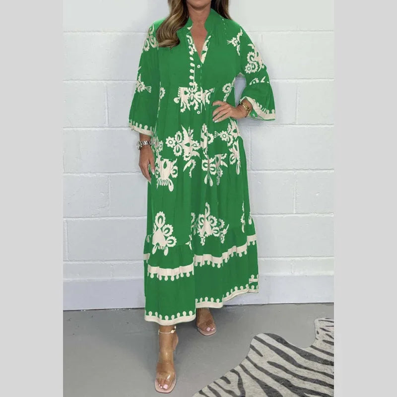Robe longue verte à motifs floraux blancs, manches trois-quarts, portée par une femme. Mode féminine élégante, tendance été, style bohème chic.