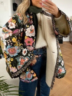Femme portant un manteau floral coloré, doublé de fourrure, avec un pull blanc et un jean. Mode automne-hiver, style bohème chic, tendance 2023.