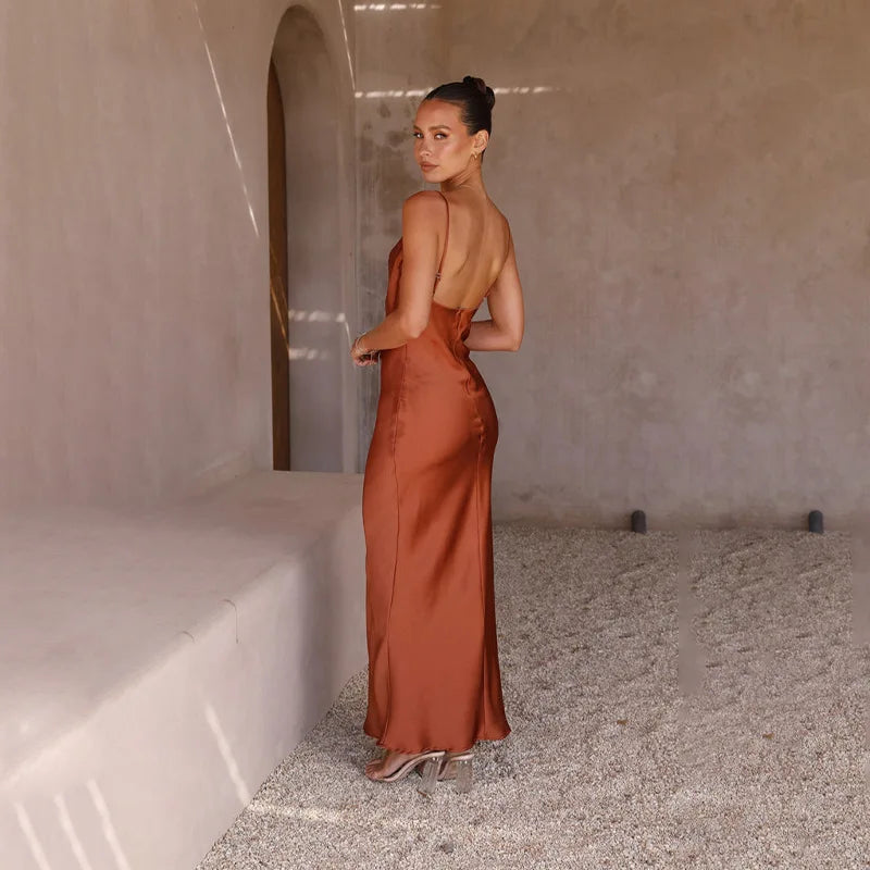 Robe longue dos nu en satin marron, femme élégante posant dans un décor minimaliste, lumière naturelle, mode chic et sophistiquée.